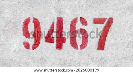 Red Number 9467 on the white wall. Spray paint. Number nine thousand four hundred and sixty seven.