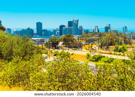 Blooming foliage fills the hillsides of San Diego County and surrounds the freeway and skyline of downtown San Diego.