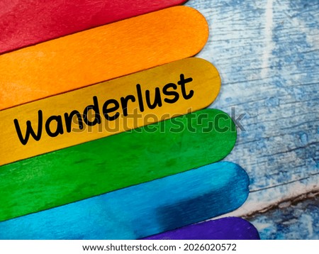 Text Wanderlust wrtiting on colored ice cream sticks on a wooden background. Trending photos concept.