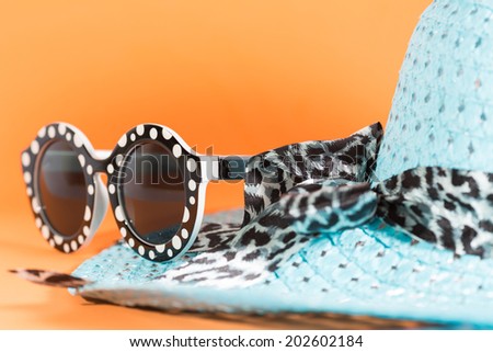 Beach hat and sunglasses with orange background