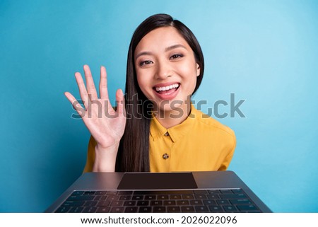 Photo of funny young brunette lady talk laptop wear yellow shirt isolated on blue color background