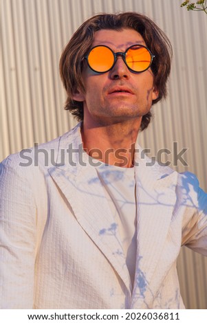 Close up portrait of a handsome man with round hippie sunglasses during sunset