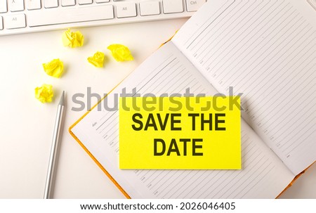 SAVE THE DATE text on sticker on diary with keyboard and pencil