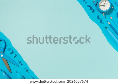 Top view photo of ordered composition blue school accessories pencils felt pens scissors pins and alarm clock on isolated light blue background with copyspace in the middle