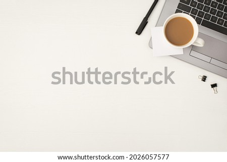 Top view photo of cup of drink binder clips sticker note on grey laptop and black pen on isolated white wooden table background with empty space