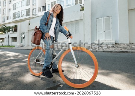 College student with big leather bag sitting on bicycle waiting for traffic light