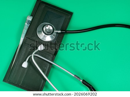 Medical and business concept. Layout of stethoscope and wallet with cash reference to medical bills. Selective focus points