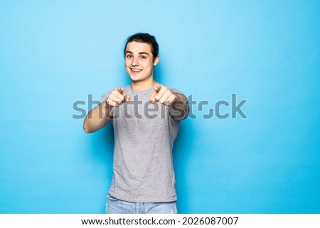 Young handsome man over blue background pointing to you and the camera with fingers