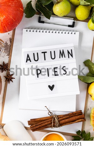 Autumn flat lay with lightbox with the phrase Autumn pies. Top view. Food ingredients for making autumn pumpkin pie on a white stone background.