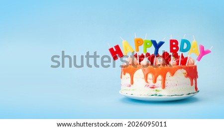 Birthday cake with happy bday candles on a blue background with copy space for your greetings