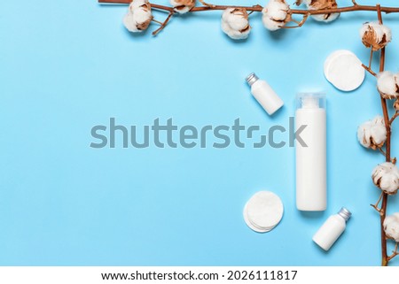 Cotton flowers with cosmetics and pads on color background