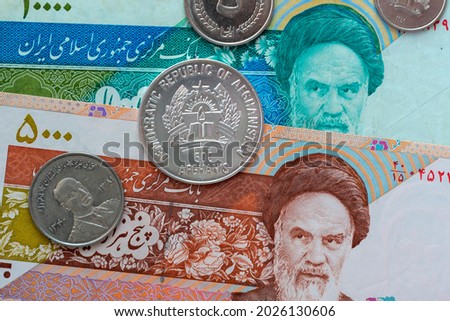 Afghani coin (Afganistan money) on top of Iran rials bills for financial and investment concepts