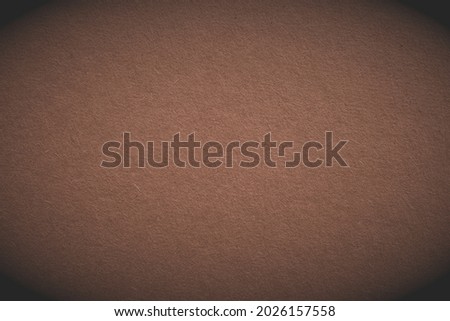 The surface of brown cardboard. Paper texture with cellulose fibers. Spicy mix color background with vignetting. Paperboard wallpaper. Textured graceful backdrop. Top-down. Macro