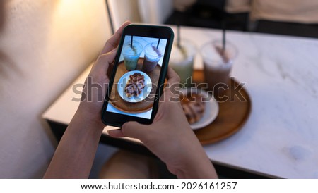 Top view. Woman Taking a photo of the mini sweets cake and coffee with a mobile smartphone. Photography with Mobile Phone and relaxation on holiday travel concept.