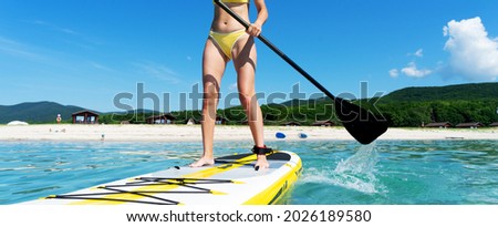 Closeup female surfer legs standing on surfboard enjoying sup surfing floating at sea water