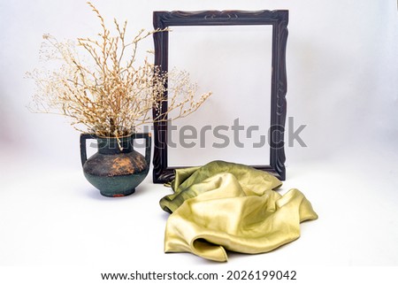 empty frame mock up with a green silky scarf and a vintage vase with dried flower and branches