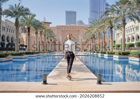 Enjoying travel in United Arabian Emirates. Young woman with camera walking on Dubai Downtown. Royalty-Free Stock Photo #2026208852