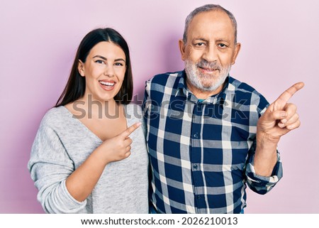 Hispanic father and daughter wearing casual clothes cheerful with a smile on face pointing with hand and finger up to the side with happy and natural expression 