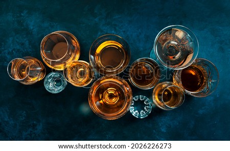 Strong alcohol drinks, hard liquors, spirits and distillates iset in glasses: cognac, scotch, whiskey and other. Blue background, top view  Royalty-Free Stock Photo #2026226273