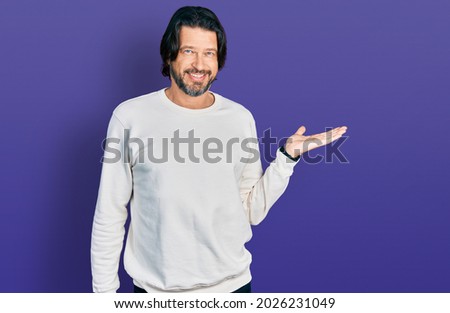 Middle age caucasian man wearing casual clothes smiling cheerful presenting and pointing with palm of hand looking at the camera. 