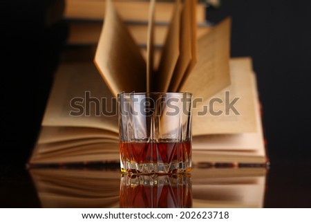 Glass of whiskey on a reflective surface with books Royalty-Free Stock Photo #202623718