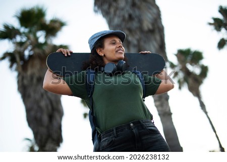 Portrait of happy african-american woman with skateboard. Young stylish woman with skateboard outdoors	