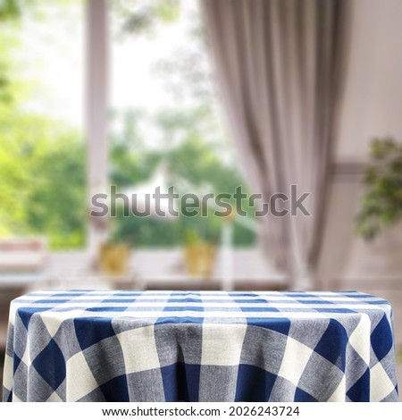 Table background with blue and white tableclothe and kitchen interior with window. Free space for your decoration 