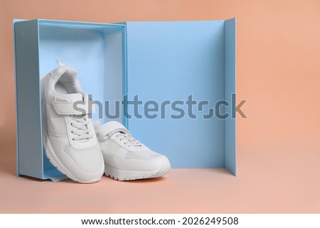 Pair of comfortable sports shoes and box on pale coral background. Space for text