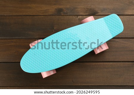 Turquoise skateboard on wooden background, top view. Sport equipment