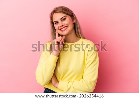 Young russian woman isolated on pink background smiling happy and confident, touching chin with hand.
