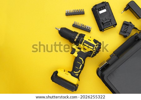 Yellow-black screwdriver on a yellow background, a set of bits. Royalty-Free Stock Photo #2026255322