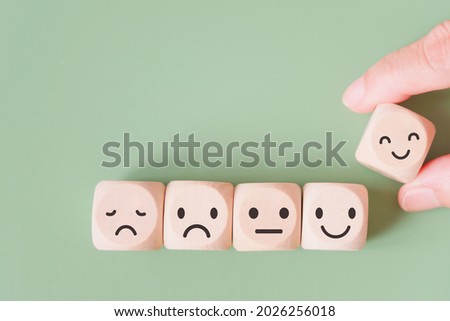 hand selected happy face wood cube and others on green background for customer service evaluation, feedback, satisfaction survey or mental heath concept Royalty-Free Stock Photo #2026256018
