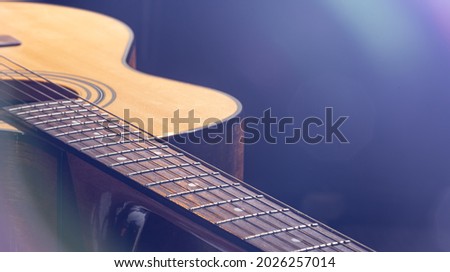 Acoustic guitar with a beautiful wood on a black background in the light of a spotlight. Royalty-Free Stock Photo #2026257014