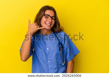 Young nurse woman isolated on yellow background  showing a mobile phone call gesture with fingers.