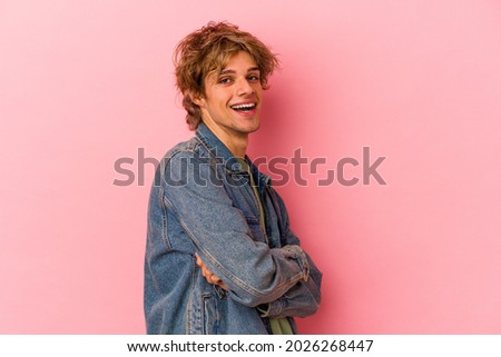 Young caucasian man with make up isolated on pink background who feels confident, crossing arms with determination.