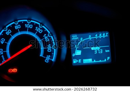Automobile dashboard in neon light at night. Neon light in blue of car milage and speed panel during parking and many of safety icon and car status signal appearance Royalty-Free Stock Photo #2026268732