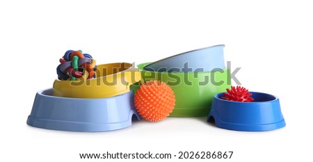Feeding bowls and dog toys on white background