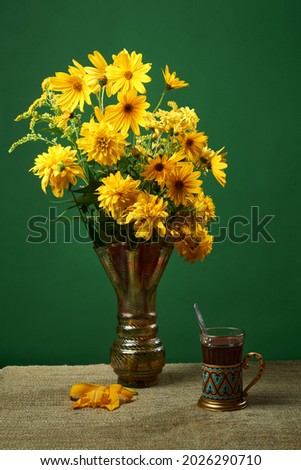 A bouquet of yellow flowers in a vase and tea