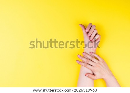 Female hands with a trendy autumn french manicure with red tips at the free edge of the nail. Ultimat yellow background Royalty-Free Stock Photo #2026319963