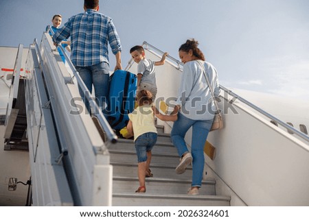Back view of parents with two kids getting on, boarding the plane on a daytime, ready for summer vacations. People, traveling, vacation concept Royalty-Free Stock Photo #2026324601