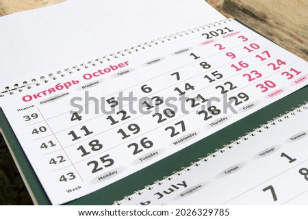 Planning a business calendar for October 2021 paper wall business concept with English and Russian text. Royalty-Free Stock Photo #2026329785