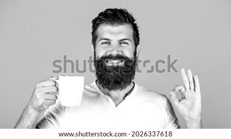 Good morning, man tea, ok. Smiling hipster man with cup of fresh coffee, Happy man showing ok sign. Morning concept. Black and white.