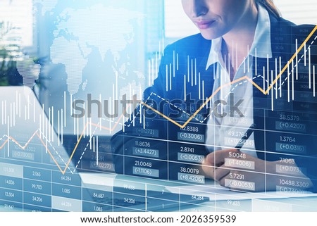 Businesswoman wearing formal suit is taking notes on list of paper and working on laptop. Financial graph and chart with map of the Earth. Office in the background. Concept of international trading