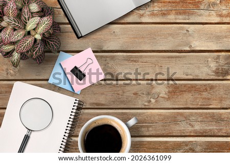 Open book, a cup of coffee, flowers on an old wooden table. Office desk table.