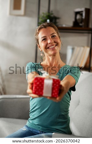 Happy woman holding gift box. Portrait of beautiful smiling woman holding a gift	