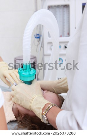 Resuscitator holds an oxygen mask on child's face. General anesthesia. Preparing for surgery. Vertical photo. Life saving. Artificial lung ventilation apparatus.