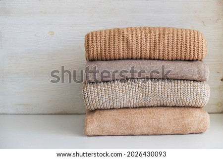 Bunch of knitted warm pastel color sweaters with different knitting patterns folded in stack, clearly visible texture. Stylish fall-winter season knitwear clothing. Close up, copy space for text. Royalty-Free Stock Photo #2026430093