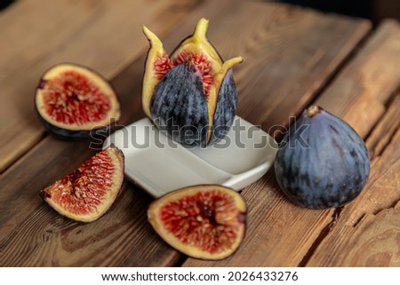 Fresh cut purple figs on a wooden background from old boards. Raw exotic figs. Low key