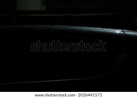 The roof of SUV car have splash raindrop in night background. It has shadow at side then make eye focus on this roof and shape of car. 