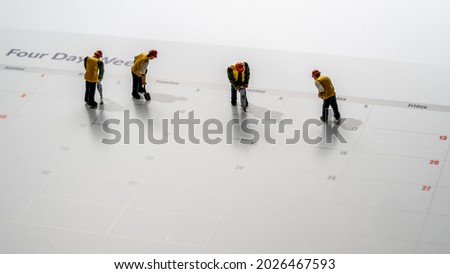 Printed calendar for a 4 day working week showing weekend days in red with small workmen working in the workweek Royalty-Free Stock Photo #2026467593